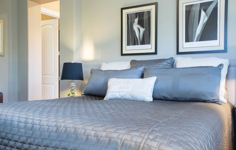 Blauwgrijze kussens op een zomers bed.